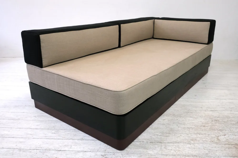 aus Kuben aufgebautes Sofa/Tagesbett mit runder Ecke, Leinenbezüge Schwarz/leinenfarbig, Holzsockel mit schwarz gebeiztem Funier und rotbraunem Linoleum. 30er JahreLinoleum