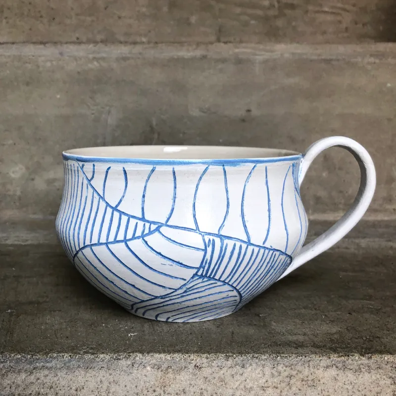 Beatrice Behrens Weisse Steinzeugtasse mit Sgraffito-Technik gestaltete Oberfläche