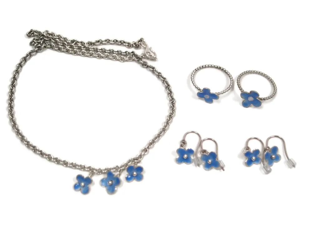 Silberschmuckkollektion aus Ketten, Ringen und Ohrringen. Die Motive sind hellblau emaillierte Blumen.